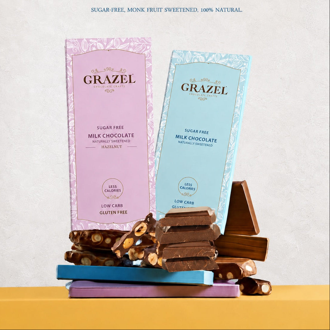 Two GRAZEL chocolate bars, one milk chocolate in a pink wrapper and one milk chocolate in a light blue wrapper, displayed with broken chocolate pieces on a yellow surface against a textured off-white background. The text 'NATURALLY SWEETENED' is printed at the top.